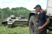 Un fermier remorque un blindé de transport de troupes russe abandonné près du village de Mala Rogan, dans la région de Kharkiv, le 28 juillet 2022
