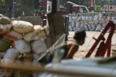 Des manifestants se mettent à couvert derrière des barricades face aux forces de sécurité, le 19 mars 2021 à Rangoun, en Birmanie