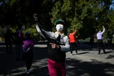 Des femmes portant des masques de protection dansent dans un parc de Pékin, le 13 mars 2020