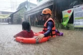 Un agent des garde-côtes aide une habitante de Cagayan de Oro, dans l'île philippine de Mindanao, à évacuer son domicile pendant des inondations apportées par le super-typhon Rai, le 16 décembre 2021