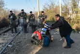 Un homme poussant la chaise roulante d'un migrant traverse la frontière entre la Grèce et la Macédoine près de Gevgelija le 4 décembre 2015