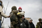 Un militaire ukrainien porte un enfant tout en aidant les gens à traverser un pont détruit alors qu'ils évacuent la ville d'Irpin, au nord-ouest de Kiev,  le 5 mars 2022

