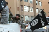 Une image diffusée par l'organe de presse jihadiste Welayat Raqa le 30 juin 2014 montre un membre du groupe État islamique (EI) défila un drapeau de l'EI à la main dans une rue de la ville syrienne de Raqa. 