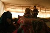 Shamayel (c), tisseuse de tapis kilim et mère de famille, sous la tente d'un camp pour déplacés près de Mazar-i-Sharif, le 28 novembre 2019 en Afghanistan