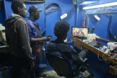 Des clients d'un coiffeur regardent à la télévision la conférence de presse du président Macky Sall, le 22 février 2024 à Dakar, au Sénégal