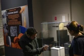 Les archéologues Murat Türkteki, à gauche, et Deniz Sari, à droite, observent un pain carbonisé vieux de 5.000 ans exposé au musée archéologique d'Eskisehir, en Turquie, le 23 mai 2025