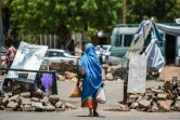 Une Soudanaise passe entre des barricades faites de pierres et de briques près du sit-in organisé par les manifestants soudanais devant le QG de l'armée à Khartoum, le 14 mai 2019