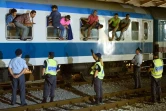 Des policiers croates regardent des migrants assis à califourchon sur les fenêtres d'un train, le 17 septembre 2015 à Dobova, près de la frontière avec la Serbie