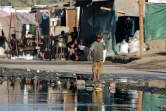 Un jeune Palestinien marche pieds nus près d'eaux usées stagnantes à Deir el-Balah, dans le centre de la bande de Gaza, le 19 juillet 2024
