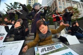 Des manifestants portent des masques à l'effigie de la présidente sud-coréenne Park Geun-Hye et de sa confidente Choi Soon-Sil à Séoul, le 29 octobre 2016 pour dénoncer un scandale de corruption impliquant les deux femmes