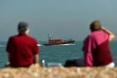 Un couple observe un bateau du secours en mer britannique sur la plage de Dungeness, le 7 septembre 2021, dans le sud-est de l'Angleterre
