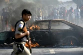 Un policier passe devant une voiture brûlée lors d'une manifestation contre la hausse du prix du diesel à Ribeirao das Neves au Brésil, le 25 mai 2018