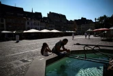 Des personnes se rafraîchissent à une fontaine publique dans une rue de Mulhouse, pendant un épisode de canicule, le 22 août 2023