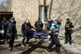 Un corps est porté sur une civière vers une école de Boutcha, près de Kiev, le 4 avril 2022