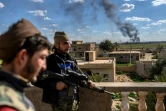 Des membres des Forces démocratiques syriennes (FDS) et au loin le village de Baghouz, dernier réduit du groupe Etat islamique bombardé, le 3 mars 2019