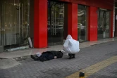 Un membre des services de secours examine le corps d'un homme mort dans la rue à Wuhan, le 30 janvier 2020 en Chine