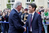 Michel Barnier sert la main du Premier ministre sortant Gabriel Attal lors de la cérémonie de passation de pouvoir à l'Hotel Matignon à Paris, le 5 septembre 2024 