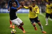 Le défenseur français Djibril Sidibé (g) aux prises avec l'attaquant colombien Luis Muriel lors du match amical, au Stade de France à Saint-Denis, le 23 mars 2018 