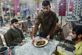 Un serveur apporte une assiette de kebabs à des clients du restaurant Tory Kebab House à Namak Mandi, dans le coeur gastronomique de Peshawar, le 13 décembre 2018