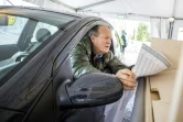 Un automobiliste remplit son bulletin de vote pour les législatives aux Pays-Bas, dans un bureau de vote réservé aux voitures et vélos à Heerlen le 15 mars 2021
