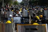 Des manifestants anti-coup d'Etat se protègent derrière des boucliers artisanaux, le 8 mars 2021 à Rangoun