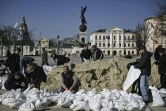 Des employés municipaux remplissent des sacs de sable pour les disposer autour de momuments qu'ils espèrent protéger des bombardements russes, le 26 mars 2022 à Kharkiv (est de l'Ukraine)