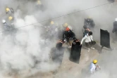 Des manifestants pris dans la fumée de gaz lacrymogènes envoyés par les forces de l'ordre et de gaz d'extincteurs utilisé par certains manifestants, à Rangoun, le 6 mars 2021