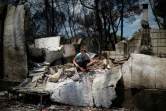 Une femme tente de récupérer quelques effets personnels dans les décombres de sa maison, le 25 juillet 2017 à Neos Voutzas. 