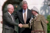 Le Premier ministre israélien Yitzhak Rabin et le leader de l'Organisation de libération de la Palestine (OLP) Yasser Arafat se serrent la main en présence du président américain Bill Clinton (c), le 13 septembre 1993 à Washington