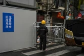 Un livreur apporte une commande à l'entrée d'un quartier confiné de Shanghai après l'apparition de nouveaux cas de Covid-19, le 17 mars 2022 en Chine