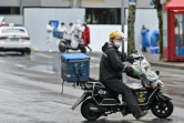 Un livreur en scooter part livrer une commande à des habitants d'un quartier confiné de Shanghai après l'apparition de nouveaux cas de Covid-19, le 17 mars 2022 en Chine