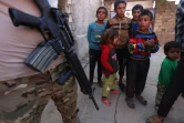 Des enfants près d'un soldat irakien patrouillant dans une rue du village de Jarif, à environ 45 kilomètres au sud de Mossoul, le 12 novembre 2016