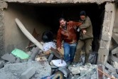 Deux syriens sortent des décombres d'un immeuble après des bombardements dans le quartier d'al-Hamra à Alep, tenu par les rebelles, le 20 novembre 2016 