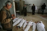 Un Syrien prie près des corps de civils tués par des raids du régime sur le fief rebelle de la Ghouta orientale, avant leur enterrement, le 20 février 2018