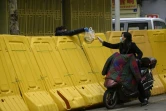 Une femme achète des bananes à une vendeuse située de l'autre côté de la barricade, à Wuhan le 2 avril 2020