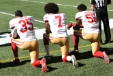 Les joueurs des Francisco 49ers  Eric Reid (g) Colin Kaepernick (c) et Eli Harold genou à terre pendant l'hymne national, le 25 septembre 2016 à Seattle