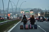 Des voyageurs se rendent à pied à l'aéroport Orly, le 17 décembre 2016 en raison du blocage de l'autoroute par les chauffeurs de VTC 