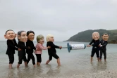 Des militants avec des masques à l'effigie des dirigeants du G7 se disputent une seringue de vaccin contre le Covid-19 lors d'une action menée par Oxfam, à Falmouth, le 11 juin 2021