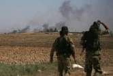Des combattants syriens proturcs regardent la fumée s'élever de la ville de Tal Abyad dans le nord de la Syrie, le 12 octobre 2019 