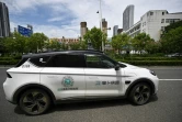 Un robotaxi (g), véhicule autonome sans chauffeur, du projet "Apollo Go" du géant technologique chinois Baidu, dans une rue de Wuhan, le 1er août 2024 dans la province chinoise du Hubei