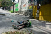 Une femme passe devant un corps abattu par balle, le 28 mars 2024 à Port-au-Prince