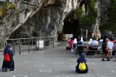 Des pélerins prient devant la Grotte du sanctuaire de Lourdes, le 14 août 2020  dans les Hautes-Pyrénées