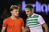 Roger Federer (d) quitte le court accompagé par son adversaire, le Belge David Goffin, éliminé par le Suisse à l'Open d'Australie, le 24 janvier à Melbourne