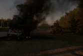 Un blindé de l'armée ukrainienne près d'un véhicule en feu, à proximité de la frontière avec la Russie, dans la région de Soumy le 14 août 2024