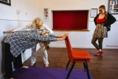 Dorothea Barron, 100 ans, vétérane britannique de la Seconde Guerre mondiale, aide une élève à étirer son dos lors d'un cours de yoga près de Harlow, le 31 mars 2025 au nord de Londres