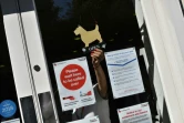 Une employée de la Croix-Rouge britannique place le panneau "ouvert" sur la vitrine d'un magasin, le 25 juin 2020 à Londres