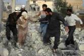 Des secouristes syriens aident une femme blessée à se sortir des décombres, après une frappe aérienne des forces gouvernementales contre le quartier d'Hadariya tenu par les rebelles, le 10 avril 2016 à Alep