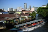 Une navette fluviale longe un quartier pauvre de Bangkok, tout près de buildings modernes, le 13 mars 2019