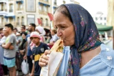 Une femme mange un sandwich préparé par le vendeur de street food Habib el-Bey le 2 juillet 2022 sur l'avenue Habib Bourguiba, à Tunis 
