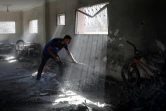 Un Palestinien nettoie à la pelle les décombres d'un bâtiment touché par un bombardement à Nousseirat, dans le centre de la bande de Gaza, le 12 août 2024